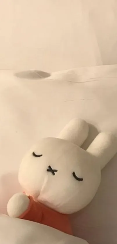 Cute white bunny plushie sleeping on a bed.