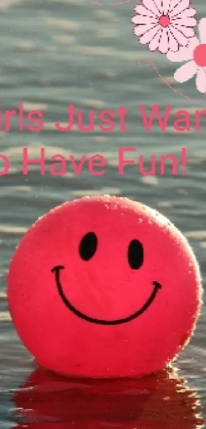 Cheerful pink smiley face ball on beach water reflecting fun.