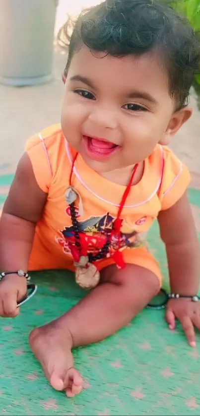 Adorable baby in orange outfit with a happy smile.