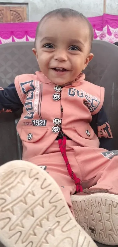 Smiling baby in pink outfit, joyful and cute.