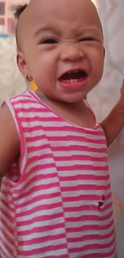 Baby wearing pink striped shirt with cheerful expression.