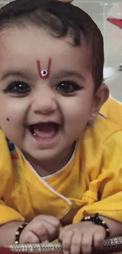 Smiling baby in a bright yellow outfit, exuding joy.