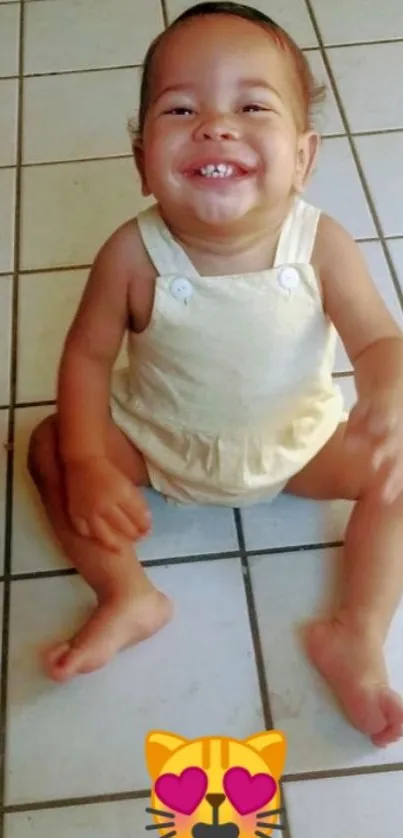 Smiling baby in beige outfit sits on a tiled floor.