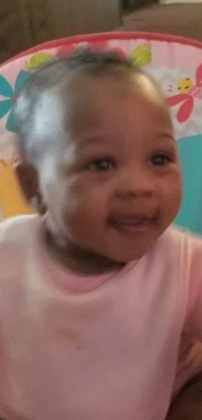 Smiling baby in pink onesie with colorful toys.