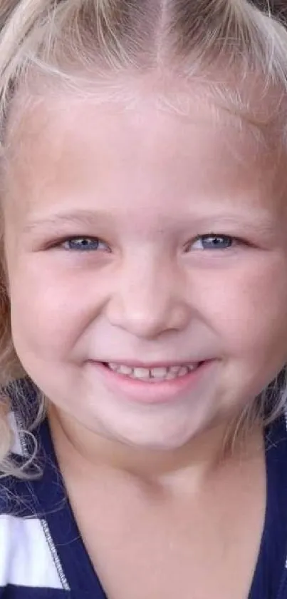 Adorable blonde child smiling with blue eyes and curly hair.