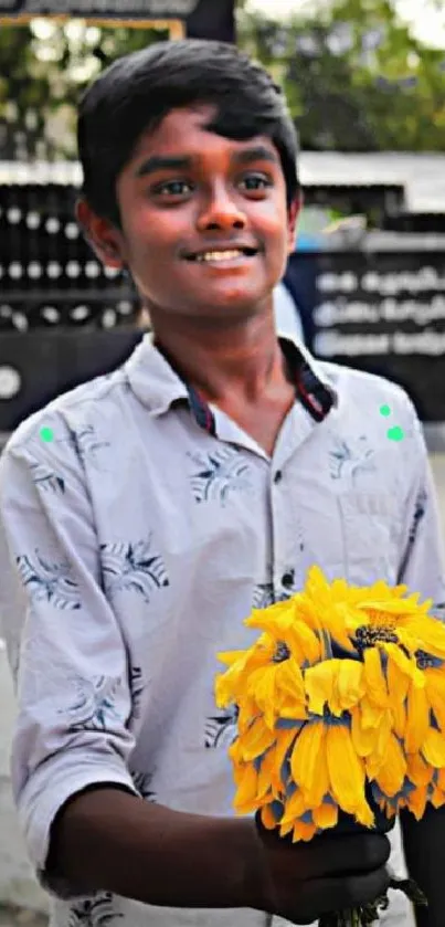 Young boy smiling, holding a bunch of yellow flowers.