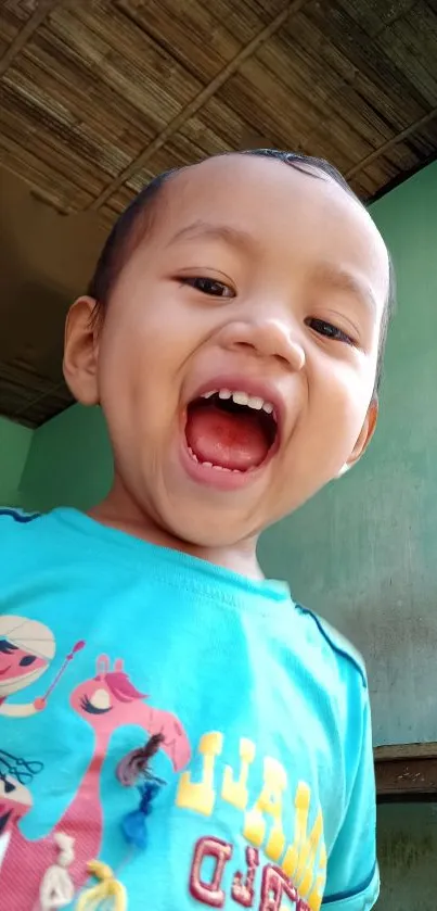 Joyful child in animated blue shirt smiling widely.