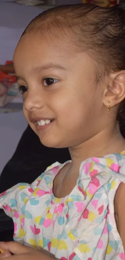 Smiling child with heart-patterned dress.