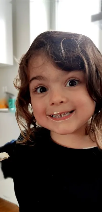 Child smiling in a cozy kitchen setting with playful expression.