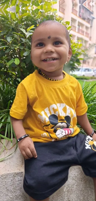 Smiling child in a Mickey Mouse shirt outdoors.