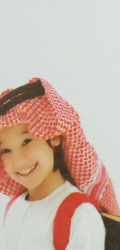 Smiling child in traditional attire with a backpack on a bright background.