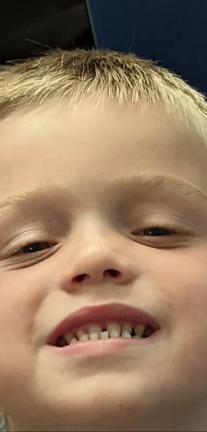 Mobile wallpaper of a smiling child with blonde hair against a blue and beige backdrop.