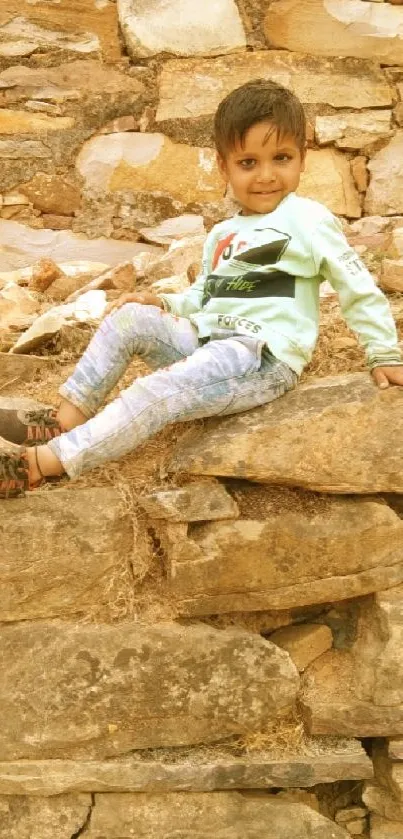 Child smiling on rustic stone wall with earthy tones.