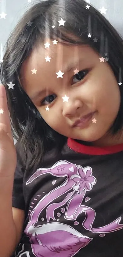 Child smiling with peace sign, black and pink shirt.