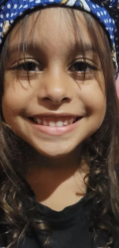 Smiling child in a colorful blue hat portrait.