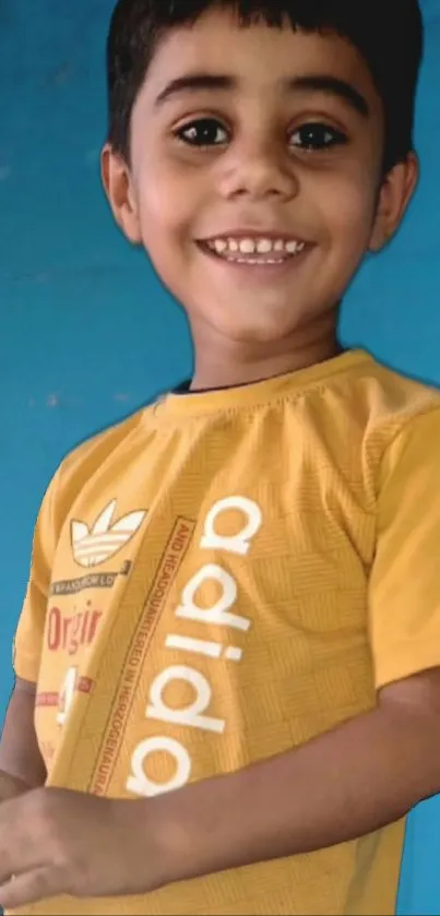 Smiling child in yellow shirt with blue background.