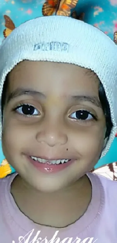 Smiling child in a white hat with colorful butterflies.
