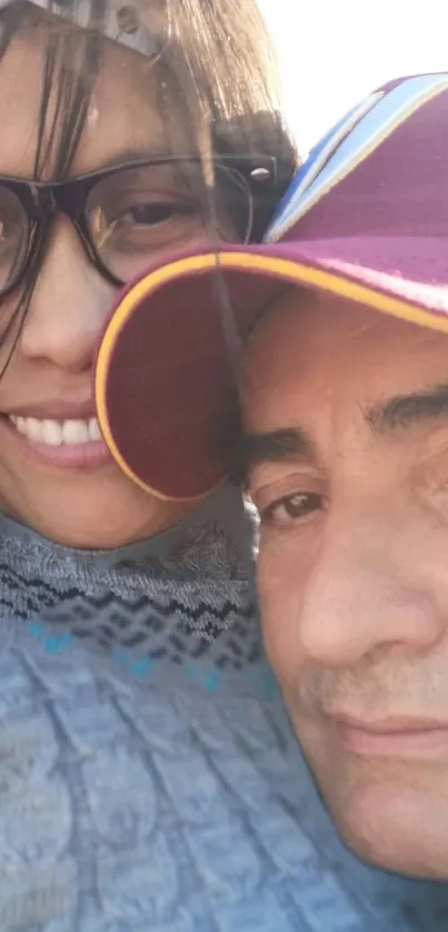 Smiling couple in sunlight wearing glasses and hats.