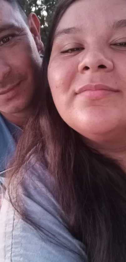 Close-up portrait of smiling couple with soft pink background.