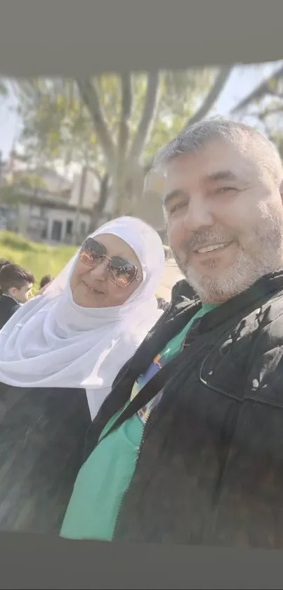 A cheerful couple smiling in a sunny outdoor setting.