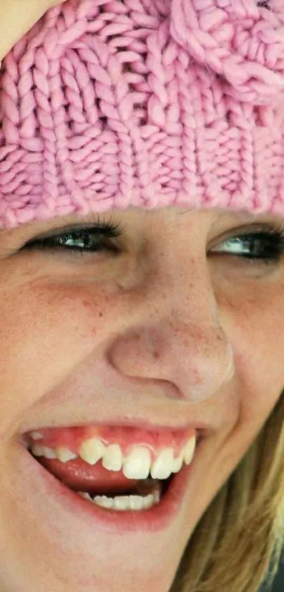 Smiling girl wearing a pink knit hat showcasing joy.