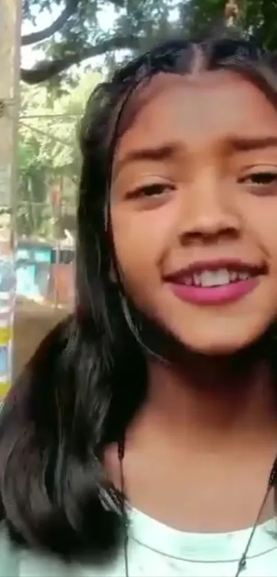 Smiling girl in an outdoor natural setting with trees.