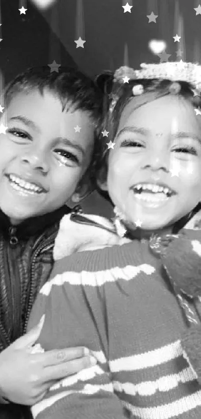 Two smiling children in a black and white photo wallpaper.