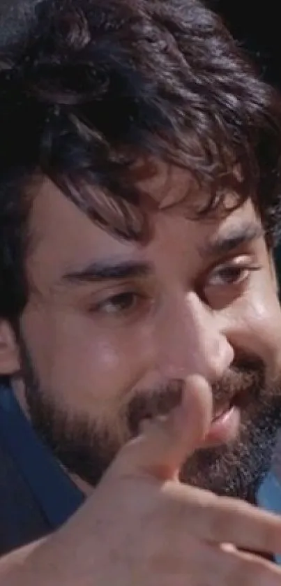 Close-up of a smiling man with a beard and dark hair in a relaxed pose.