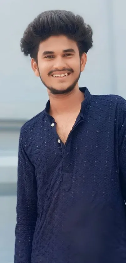 Smiling man in blue textured shirt with soft background.