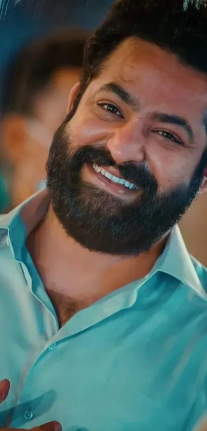 A smiling man with a beard in a blue shirt, vibrant and cheerful.