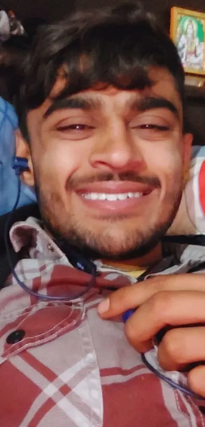 Smiling young man wearing plaid shirt with headphones.