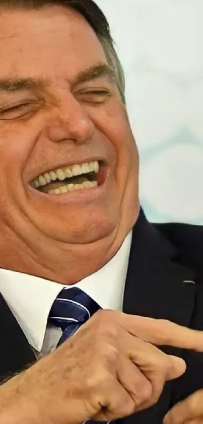 A man in a suit joyfully laughing with a light background.