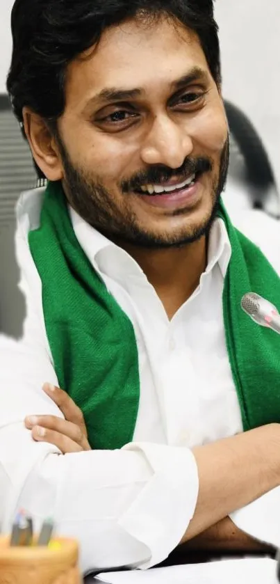 Man smiling with green scarf, arms crossed.