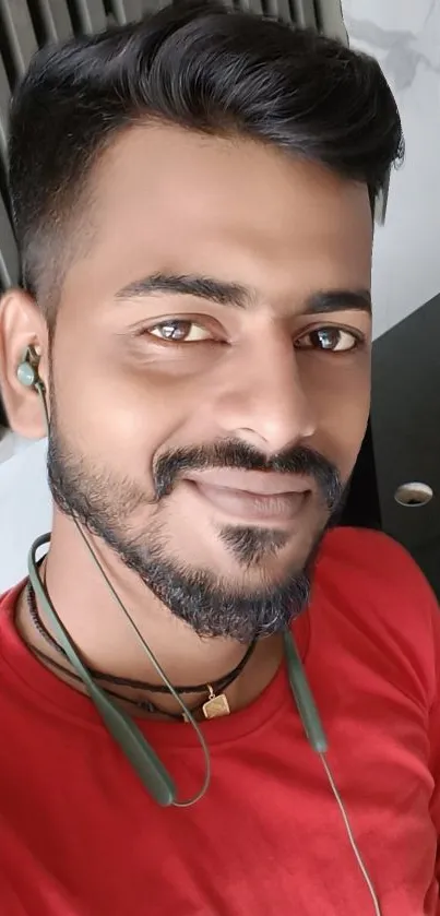 Man smiling with headphones in a red shirt.