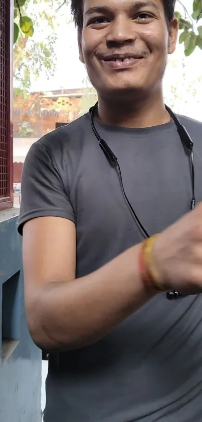 Smiling young man in gray shirt outdoors.