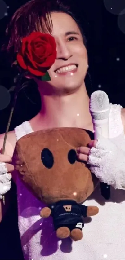 Smiling person holding a rose and plush toy on stage.