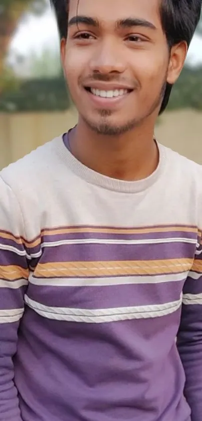 Smiling person wearing striped shirt in an outdoor setting.