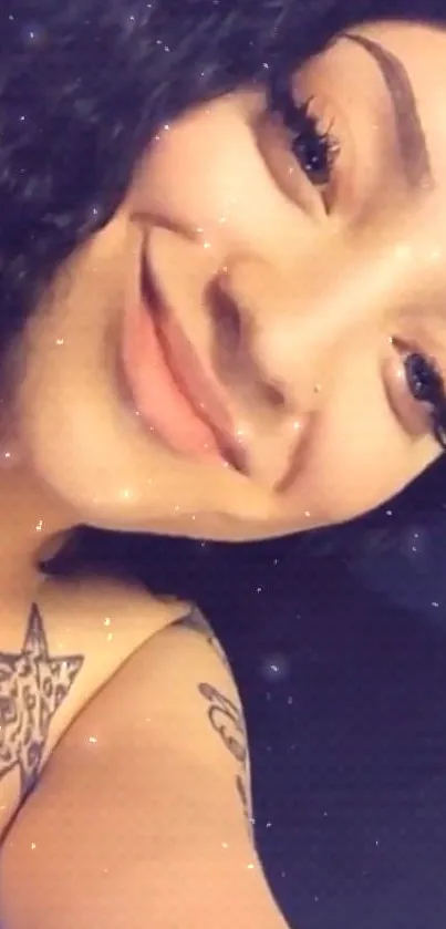 Smiling person with curly hair and tattoos, close-up wallpaper.