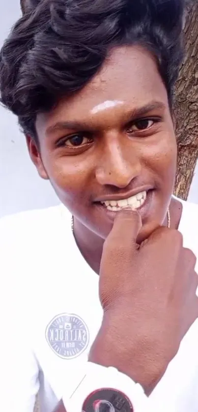 Smiling person outdoors beneath a tree.