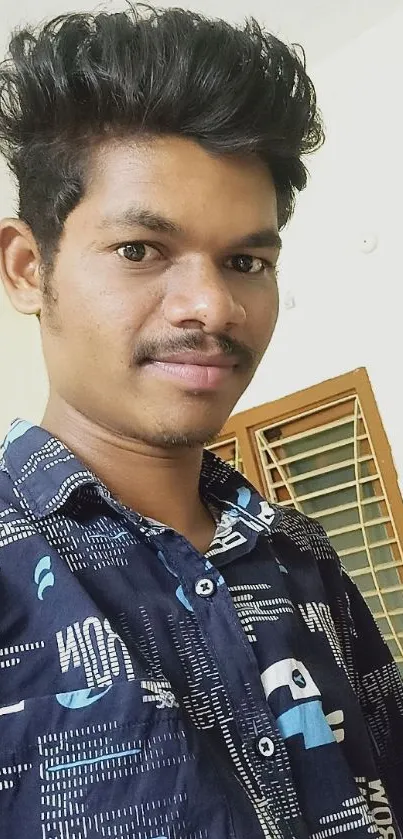 Young man in blue shirt with casual indoor background.