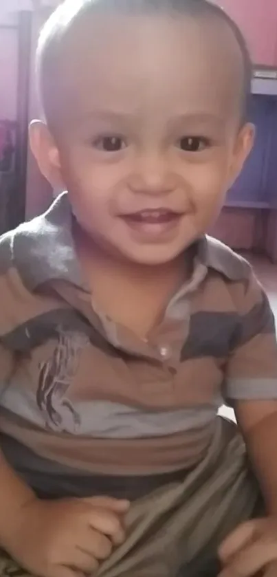 Cute toddler smiling in a striped shirt indoors.