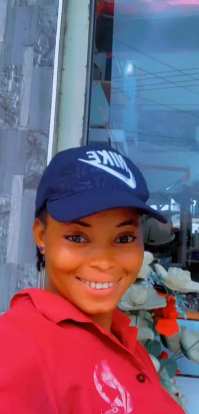 Smiling woman in a navy cap with a red shirt background.