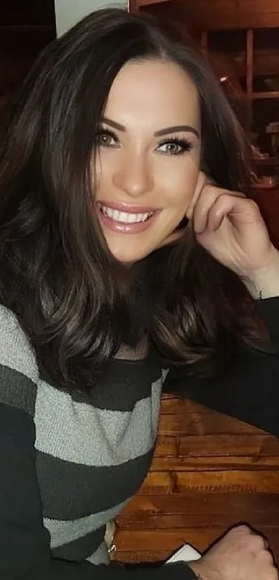 Smiling woman in striped sweater sits in cozy cafe.