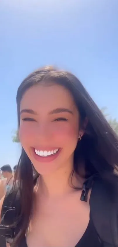 Woman smiling on a sunny beach day, palm trees in background.