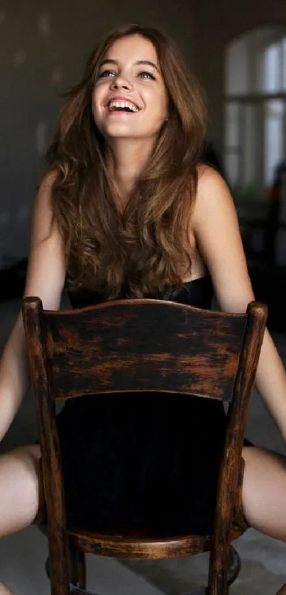 Smiling woman sitting on a wooden chair in a modern room.