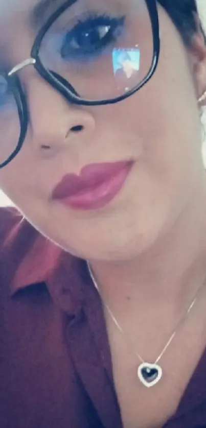 Close-up of a woman smiling with glasses and necklace.