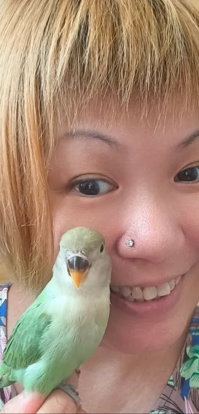 Woman smiling with a green parrot on hand.