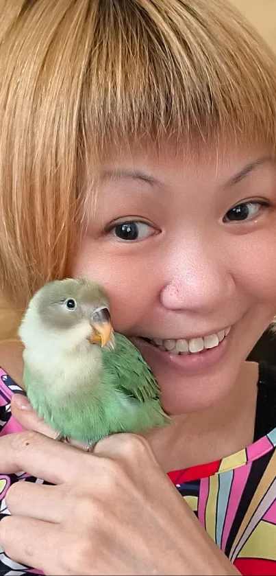 Smiling woman holding a green parrot in vibrant setting.