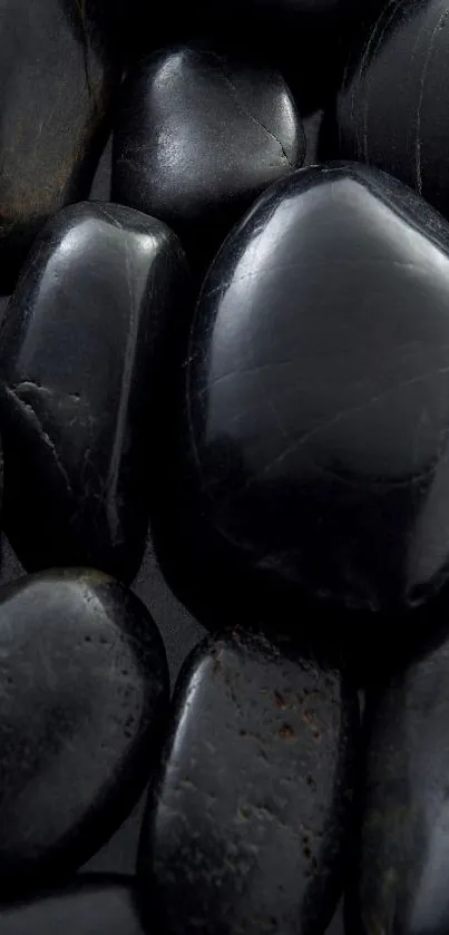 Mobile wallpaper featuring smooth black pebbles and one distinct white pebble.