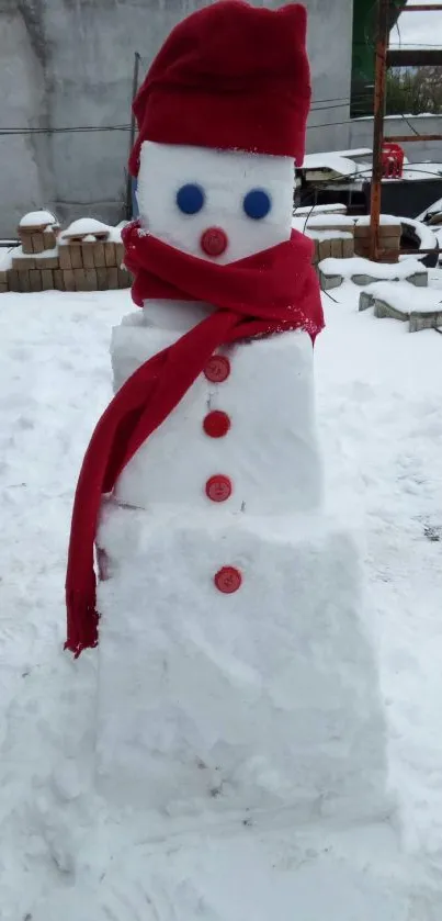 Snowman with a red scarf and hat on snowy ground.